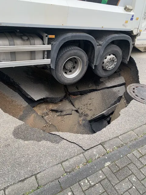 Ein plötzlich entstandenes Straßenloch ließ in Wiesenbach einen Lastwagen der Altglasabholung und einen geparkten Opel Astra absacken. Verletzt wurde niemand, die Ursache soll eine massive Unterspülung gewesen sein. | Foto: Polizeipräsidium Mannheim