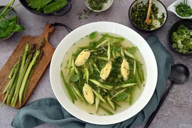 Diese Suppe mit Parmesan-Nocken sowie grünem Spargel und knackigen Kräutern bringt den Frühling in den Suppenteller.   (zu dpa: «Frühlingssuppe mit Parmesan-Nocken und Oliven-Gremolata») | Foto: dpa