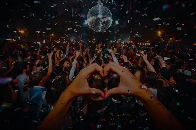 Das Bild zeigt Menschen, die eine Party feiern, mit Discokugel, Konfetti und Liebe