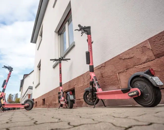 Das Bild zeigt E-Scooter an eine Hauswand gelehnt