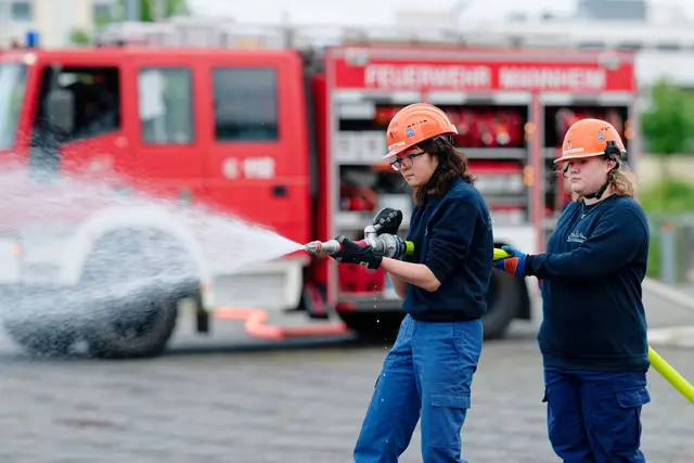 Ilias (links) und Annabella, Mitglieder der Jugendfeuerwehr in Mannheim, halten bei einer Übung einen Feuerwehrschlauch in den Händen. | Foto: Uwe Anspach/dpa