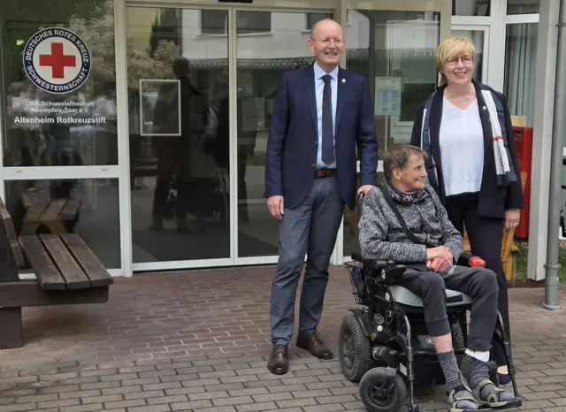 Bürgermeister Stefan Ulrich mit Einrichtungsleitung Barbara Baltus und einem Bewohner vor dem Eingang des Rotkreuzstifts. | Foto: DRK Schwesternschaft Rheinpfalz-Saar e.V.