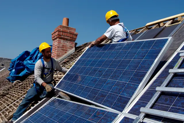 Das Bild zeigt Männer, die eine Solaranlage auf einem Dach montieren