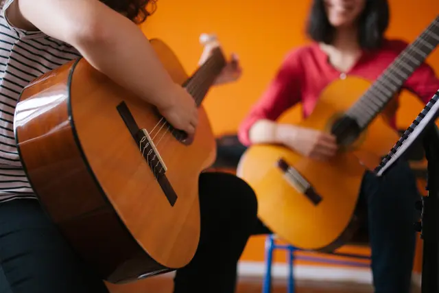 Das Bild zeigt 2 Menschen, die Gitarre spielen