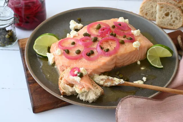 Die Marinade zum gegrillten Lachs sorgt für ein buttrig-süßes Aroma und bildet einen wunderbaren Kontrast zu den sauer eingelegten Zwiebeln und den salzigen Kapern. | Foto: dpa