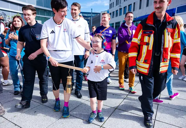 Elias (8) trägt gemeinsam mit seiner Mutter Stephanie Lade die Grubenlampe, das Symbol des Fackellaufs der Special Olympics, auf einem Holzträger durch die Saarbrücker Innenstadt. | Foto: Laszlo Pinter/dpa