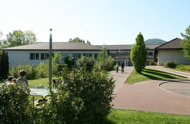 Außenansicht des Evangelischen Trifels-Gymnasiums in Annweiler am Trifels mit Eingangsbereich und Schulgelände.