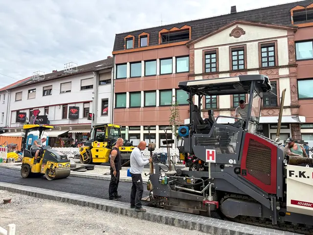 Asphaltarbeiten im dritten Bauabschnitt der Kaiserstraße in Landstuhl mit Asphaltfertiger, Straßenwalzen und Bauarbeitern beim Straßenumbau.