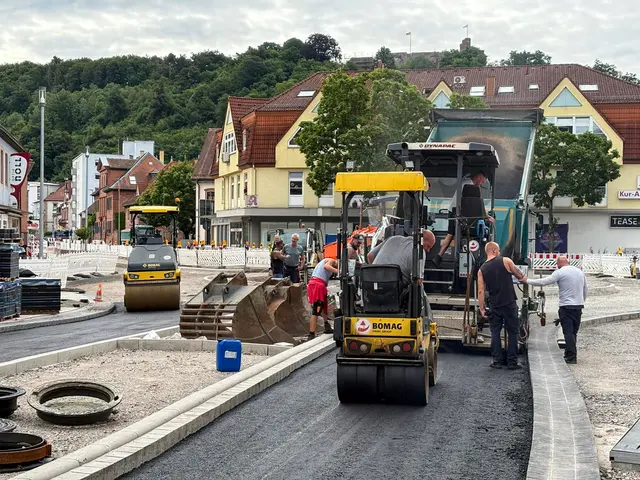 Asphaltarbeiten im dritten Bauabschnitt der Kaiserstraße in Landstuhl mit Asphaltfertiger, Walzen und Bauarbeitern während des Straßenumbaus.