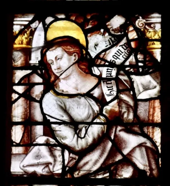 Dieser filigrane Ausschnitt eines Renaissance-Glasfensters der Église Saint-Étienne in Bar-sur-Seine bezeugt das virtuose Erbe der Schule von Troyes, die im 16. Jahrhundert die Sakralkunst der südlichen Champagne prägte. Flankiert von klassischen Pilastern verkündet die nimbierte Gestalt auf ihrem geschwungenen Spruchband das lateinische Hic est qui de celo („Dies ist [das Brot], das vom Himmel [herabgekommen ist]“), wobei das meisterhaft in Grisaille und Silbergelb fixierte Bildwerk die theologische Tiefe mit der eleganten Ästhetik des beginnenden Humanismus vereint.
 | Foto: Daniel J. Basler