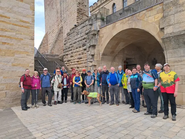 Gruppe blinder und sehbehinderter Wanderer mit Begleitpersonen vor einer historischen Burganlage während der Blinden-Wanderwoche in der Südpfalz.