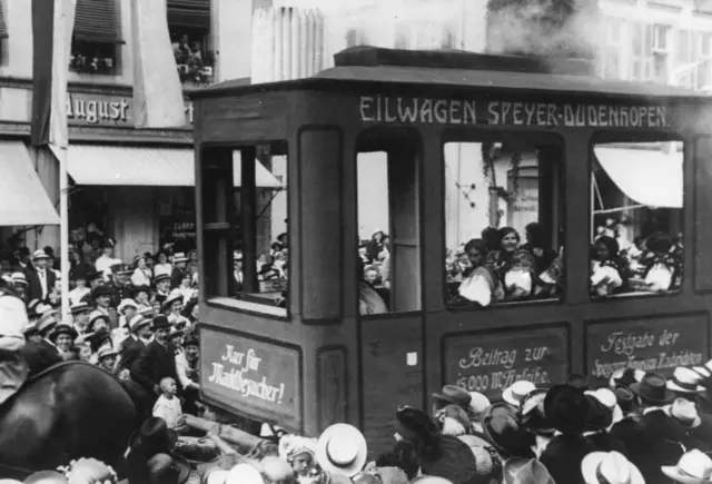 Historischer, von Pferden gezogener Wagen in Form eines Eisenbahnwaggons / Straßenbahnwaggons mit der Aufschrift: „Eilwagen Speyer - Dudenhofen Beitrag zur 15.000 Mark Anleihe, Festgabe der Speyerer Neuen Nachrichten, Nur für Marktbesucher!“ | Foto: Stadtarchiv Speyer: StASP_233-1_RegNr_009182_ArthurBarth_Brezelfestumzug_16Juli1911 