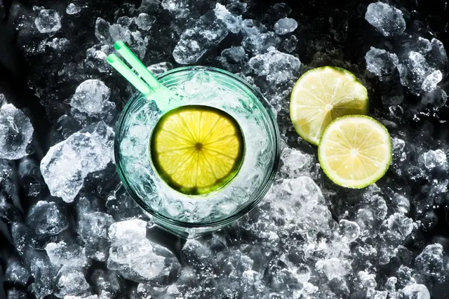 Kalorienarm trinken - Wasserglas mit Eis und Zitrone