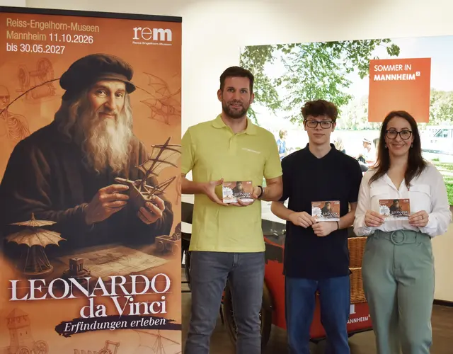 Präsentieren gemeinsam in der Tourist Information Mannheim die neue Faltkarte mit Leonardo-Ausflugstipps: Christian Förster (Leiter Tourist Information Mannheim) sowie Yannick Rosendahl und Giulia Worf (Kuratoren-Team der Leonardo-Ausstellung) | Foto: © rem gGmbH Stiftungsmuseen, Norman Schäfer 