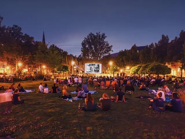 Auf dem Neumarkt in der Neckarstadt-West sitzen Menschen auf Stühlen und Decken und schauen gemeinsam einen Film unter freiem Himmel. | Foto: Stadt Mannheim/Lys-Y-Seng