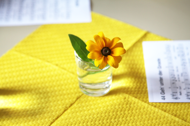Kleine Sonneblume in Glasvase, daneben Liedblatt