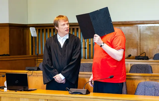 Der Angeklagte (r) steht mit seinem Verteidiger Dirk Gerlach am Verhandlungstisch im Saal 137 des Landgerichts und verdeckt sein Gesicht mit einem Aktenordner. | Foto: Laszlo Pinter/dpa