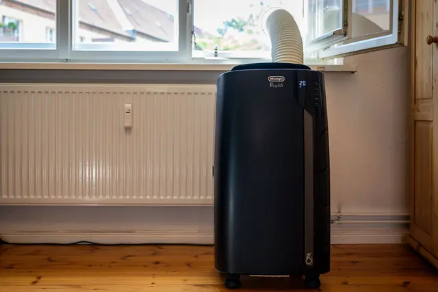 Monoblock-Klimagerät mit Abluftschlauch: Wer das Fenster abdichtet – wie hier mit einer Acrylglasscheibe mit Loch – spart Strom und kühlt effizienter. | Foto: Nico Tapia/dpa-mag