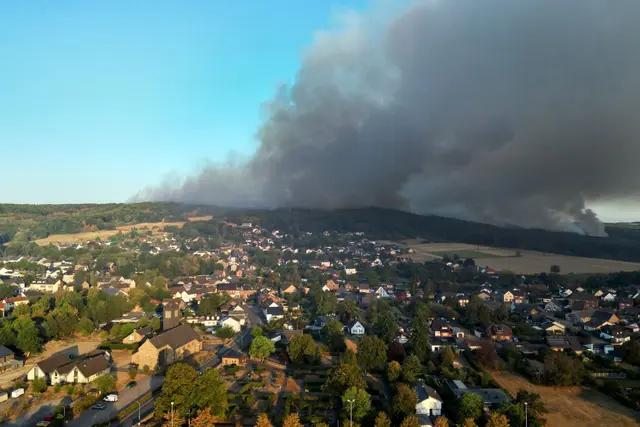 Rauch eines Waldbrands zieht über den Ortsteil Gey: Wenn das eigene Haus durch die Flammen Schaden nimmt, können Eigentümerinnen und Eigentümer auf ihre Wohngebäudeversicherung bauen. | Foto: Federico Gambarini/dpa/dpa-mag