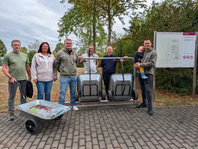 Wer Gießkannen, Erde oder Pflanzen zum Grab bringen will, kann dafür jetzt Handwagen nutzen. | Foto: Hans Bopp, Gabi Beisel, Marvin Brusius (von links) und Julian Zimprich (rechts) nahmen als Vertretende des Stadtteilvereins Pfaffengrund gemeinsam mit Vertretern der Stadt die neue Handwagenstation offiziell in Betrieb. Ab sofort können Besuchende des Fri