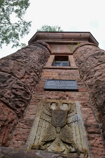 Der Blick nach oben zeigt den massiven Buntsandsteinbau des Bismarckturms. An der Fassade erinnern eine Gedenktafel und das Bismarckrelief an die Entstehung des Denkmals. | Foto: Erik Stegner