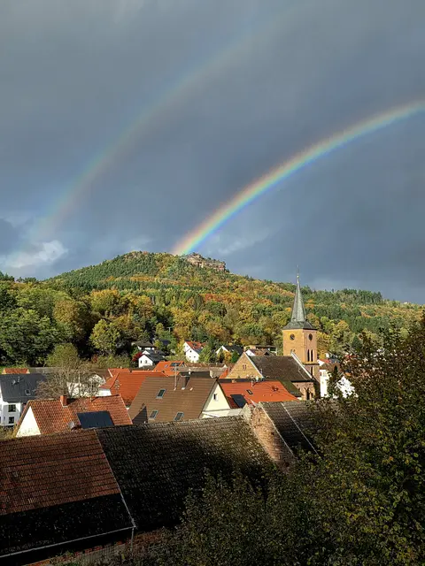 Blick über Vorderweidenthal im Pfälzerwald unter einem doppelten Regenbogen