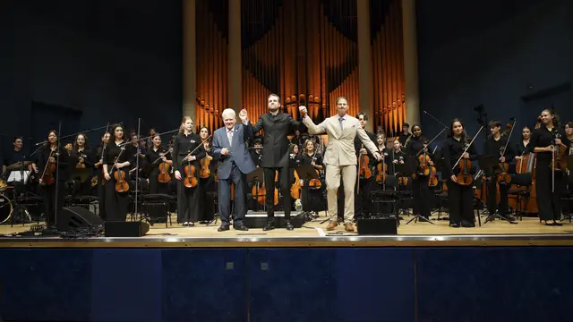 Michel Maugé (Initiator und Geschäftsführer der EYOA), Dirigent Jan-Paul Reinke und Big-Band-Leiter Thomas Siffling (v. l.) nehmen nach dem Abschlusskonzert des 1. Young European Music Festival 2026 im Mannheimer Rosengarten gemeinsam den Applaus entgegen. Im Hintergrund das Orchester der European Youth Orchestra Academy, das vom Publikum mit stehenden Ovationen gefeiert wurde. Das Konzert des Sinfonieorchesters und der Big Band fand im nahezu ausverkauften Musensaal des Mannheimer Rosengartens statt. | Foto: EYOA