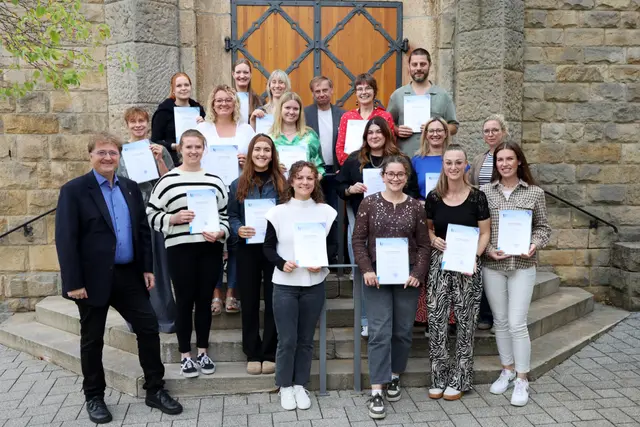 Auf der Treppe vor der Kirceh des Kloster Neustatdt stehen 16 Lehrkräfte und ihre Vokationsurkunde mit Tagungsleitung Pfarrer Michael Landgraf und Nadine Glage sowie Dr. Peter Busch, dem Leiter des Amts für Religionsunterricht