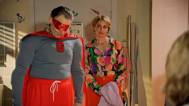 Jo Gerner steht im Superheldenkostüm neben Yvonne bei GZSZ.