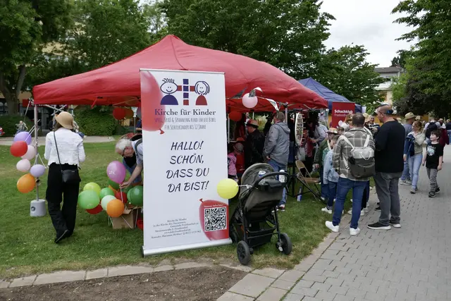 Pavillon auf dem Kinder-Strohhutfest mit Begrüßungsplakat und Luftballons.