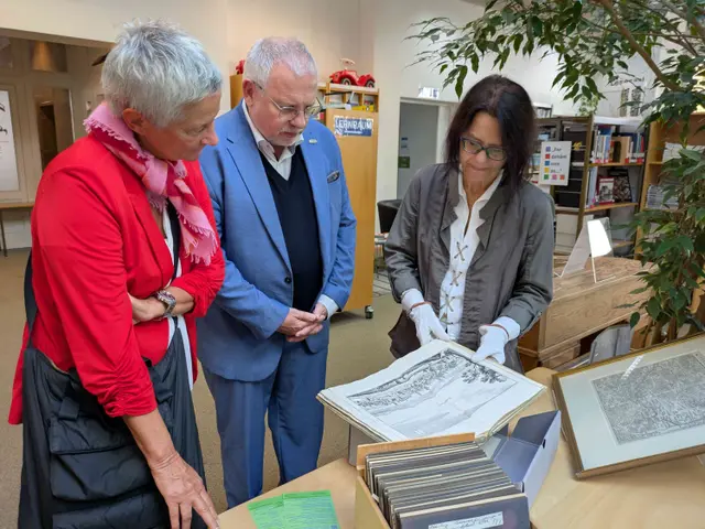 Oberbürgermeisterin Beate Kimmel und Hans-Ulrich Ihlenfeld schauen in der Pfalzbibliothek gemeinsam mit der Bibliotheksleiterin Claudia Germann auf einen historischen Stich der Stadt Kaiserslautern | Foto: Bezirksverband Pfalz/gratis