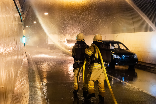 Das Szenario bei der Tunnelübung: Nach einem Zusammenstoß eines Autos mit einem Kleintransporter in der Mitte des Schlossbergtunnels brennt der Pkw – dargestellt über einen Feuersimulator. Die Feuerwehrkräfte rücken vor, um das Feuer zu löschen. | Foto: Samuel Scherer