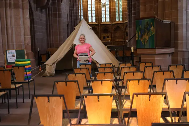 Zelt mitten in der Kirche, davor eine Frau, die viele Kinderbücher hält