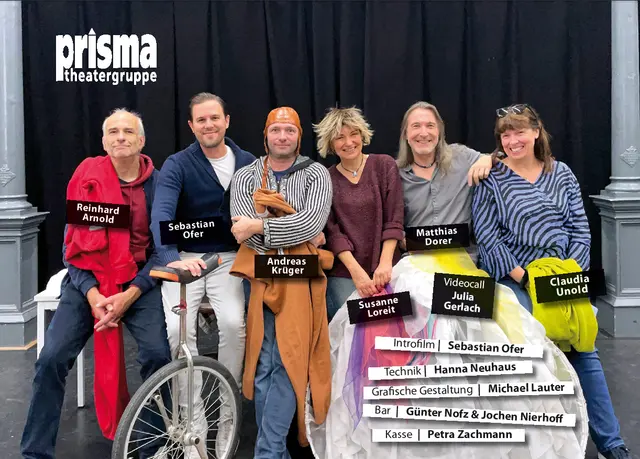 „Gruppenfoto der Theatergruppe PRISMA mit sechs Mitwirkenden vor einem schwarzen Bühnenvorhang.“
